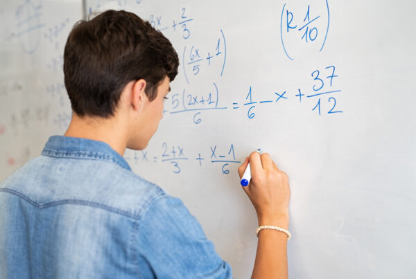 Boy at whiteboard doing a maths equation
